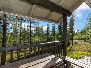Une terrasse en bois dotée d’une rambarde, qui offre une vue sur une zone boisée.