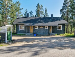 Une cabane de plain-pied avec un toit à pignon, une véranda et un petit abri attenant.
