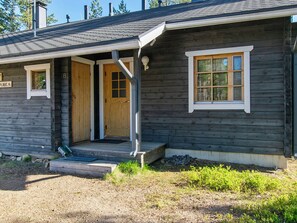 Eine Holzhütte mit einer Haustür, einem Fenster und einer Veranda.