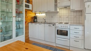 Una cocina con armarios blancos, estufa, horno y cafetera.