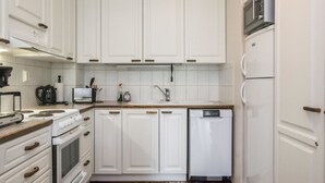 Una cuina compacta amb armaris blancs, rentaplats, microones i fogó.