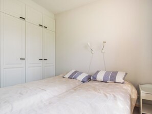 Une chambre à coucher avec un lit, deux oreillers, une table de chevet et une armoire.