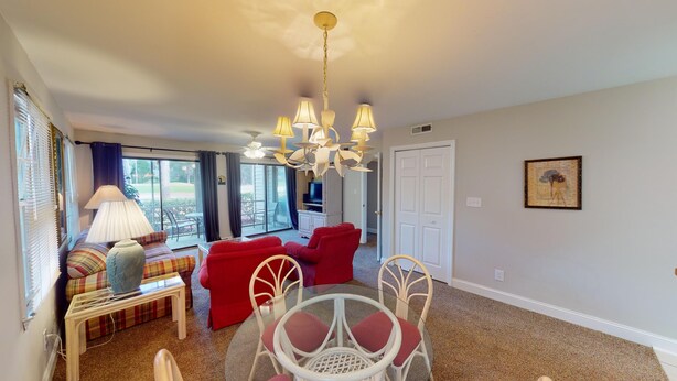 A living room with a sofa, chairs, a glass table, and a TV.