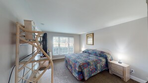 A bedroom with a bed, a desk, a chair, a window, and a picture on the wall.
