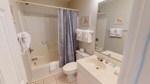 A bathroom with a bathtub, toilet, sink, and shower curtain.