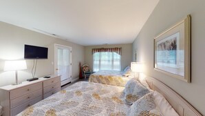 A bedroom with two beds, a TV, a dresser, and a window with blinds. - Golf Course Charm Pawleys Getaway (Pawleys Island)