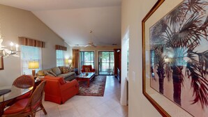 A spacious living room with a sofa, armchairs, a coffee table, and a dining area with a glass table and wicker chairs. - Golf Course Charm Pawleys Getaway (Pawleys Island)