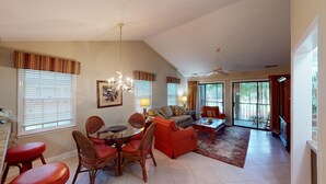 A spacious living room with a dining area, large windows, and a ceiling fan. - Golf Course Charm Pawleys Getaway (Pawleys Island)