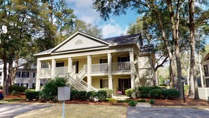 A two-story house with a balcony on the second floor, surrounded by trees. - Pawleys Plantation Greens 1 Bedroom Retreat (Pawleys Island)