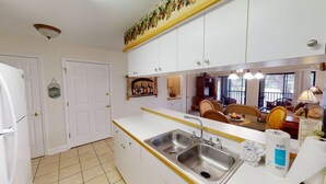 A kitchen with white cabinets, a stainless steel sink, and a tiled floor. - Pawleys Plantation Greens 1 Bedroom Retreat (Pawleys Island)
