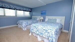 Una camera da letto con due letti, un comodino e una finestra con persiane.