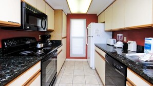 Una cucina compatta con fornello, microonde, frigorifero e lavastoviglie.