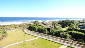 Vista sulla costa con una zona erbosa, un pontile in legno e una spiaggia sullo sfondo.