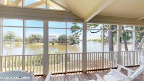 A covered outdoor area with a view of a lake and surrounding buildings. - Golf and Beach: 2BR Lakeside Villa with Lake Views (Pawleys Island)
