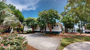 A single-story house with a front porch, a driveway, and a small garden with various plants and flowers. - Golf and Beach: 2BR Lakeside Villa with Lake Views (Pawleys Island)