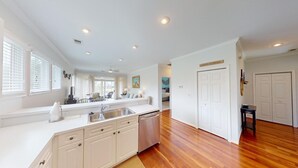 A modern kitchen with white cabinetry, a built-in dishwasher, and a large window with blinds. - Lake Views, 2BR, 2BA, Lakeside Villa (Pawleys Island)