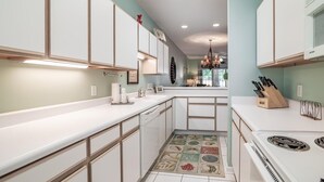 Une cuisine moderne avec des meubles blancs, un îlot central et un sol à motifs.