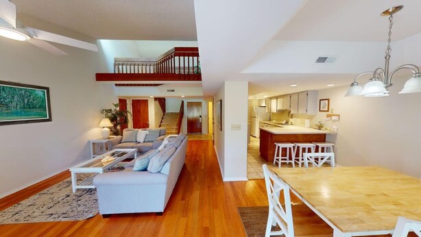 A modern apartment with a living room, dining area, kitchen, and a staircase leading to an upper level. - Beach and Golf Dreams: 3 Bedroom 2 Bath (Pawleys Island)