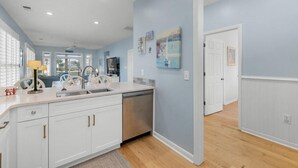 Een moderne keuken met witte kasten, een roestvrijstalen vaatwasser en een groot raam.