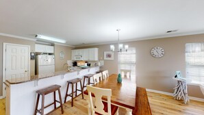 Een moderne keuken met witte kastjes, een granieten aanrechtblad en een eethoek met houten stoelen en een bank.