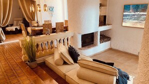 A spacious living area with a fireplace, a sofa, and a dining area with wicker furniture. - Sonne, Ruhe, Leuchtend Turkisblaues Wasser und Feinster Sandstrand (Cala Mendia)