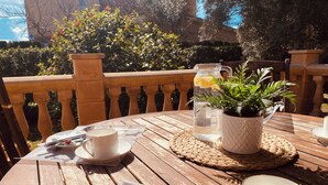 A wooden table with a placemat, a clear glass pitcher, a potted plant, and a cup. - Sonne, Ruhe, Leuchtend Turkisblaues Wasser und Feinster Sandstrand (Cala Mendia)