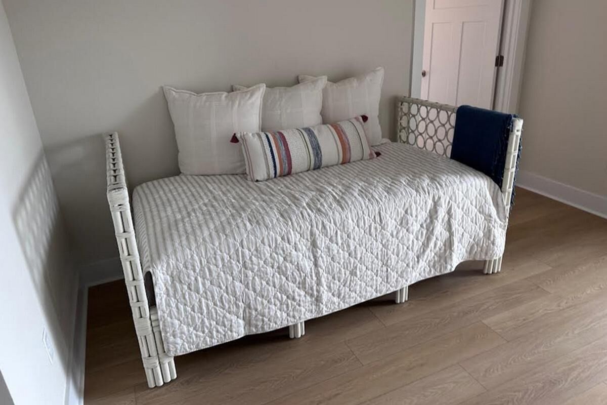 A bed with a quilted white cover, multiple pillows, and a blue throw blanket.