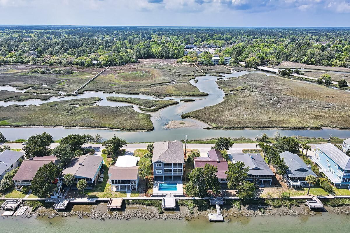 An aerial view of a coastal residential area with houses, a river, and a dock.