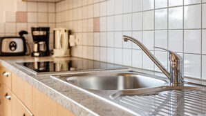 Een keuken met een roestvrijstalen spoelbak, een koffiezetapparaat en een broodrooster op het aanrecht.