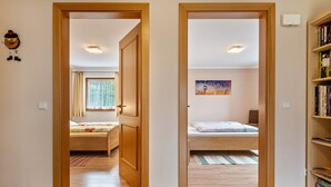 Een kamer met twee bedden, een boekenplank en een schilderij aan de muur.