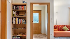 Een kamer met een boekenkast, een houten deur en een bank met kussens.