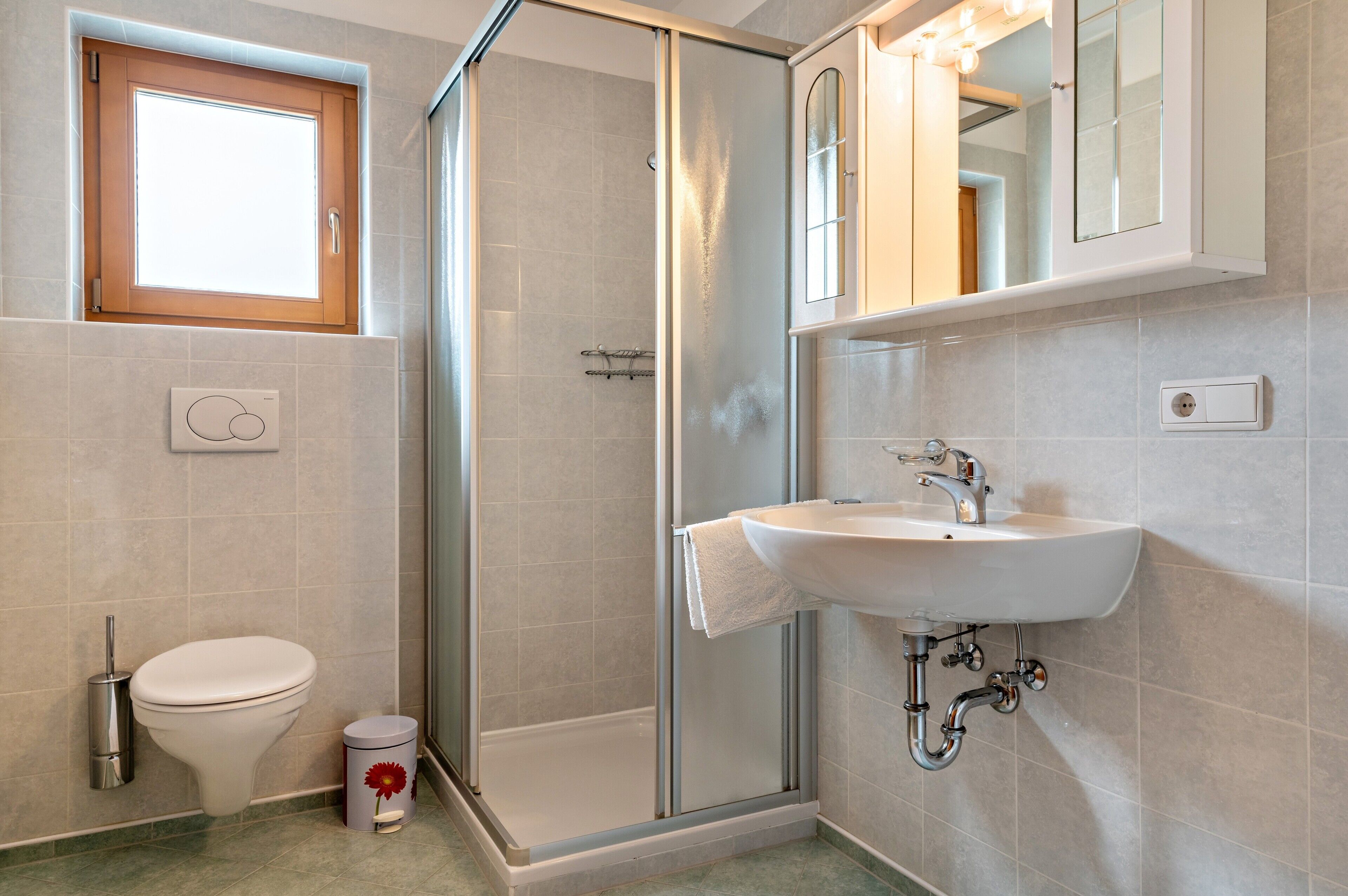 Ein Badezimmer mit Toilette, Dusche, Waschbecken und einem Fenster.
