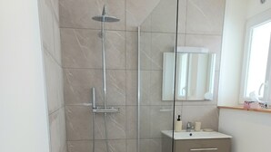 Une salle de bain moderne avec une douche à parois de verre, un meuble-lavabo avec un miroir et un évier.
