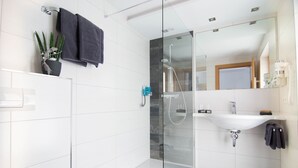 A modern bathroom with a glass-enclosed shower, a white sink, and a potted plant. - Köcks B 'n B (Galtur)