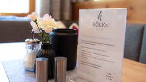 A menu board with text and a vase of flowers on a table. - Köcks B 'n B (Galtur)