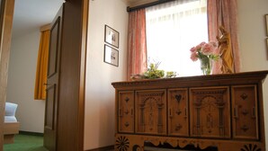 A room with a wooden cabinet, a bed, and a window with curtains. - Köcks B 'n B (Galtur)