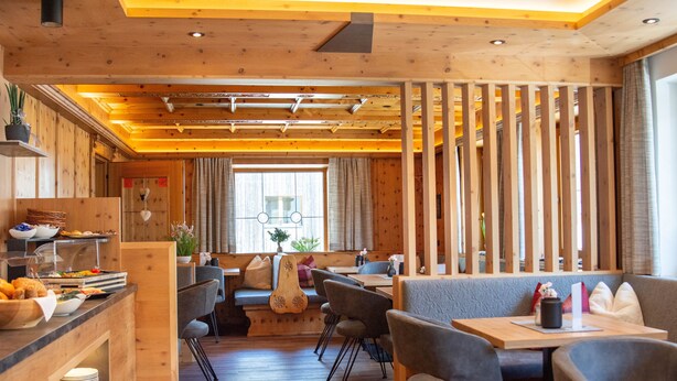A restaurant with wooden interiors, a buffet area, and seating arrangements. - Köcks B 'n B (Galtur)