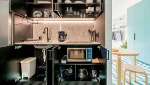 A compact kitchen with a microwave, coffee maker, and storage cabinets. - w* | Luxury 1BR in Santa Ana (Panamá)