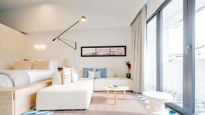 A modern hotel room with a bed, sofa, and a small table. There is a large window providing a view of the outside. - w* | Luxury 1BR in Santa Ana (Panamá)