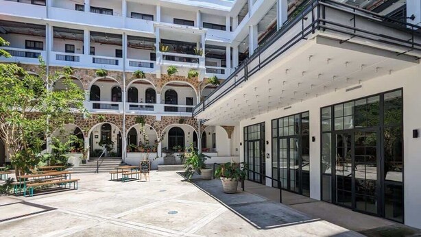 A courtyard with outdoor seating, a building with multiple balconies, and a covered area with large windows. - w* | Luxury 1BR in Santa Ana (Panamá)