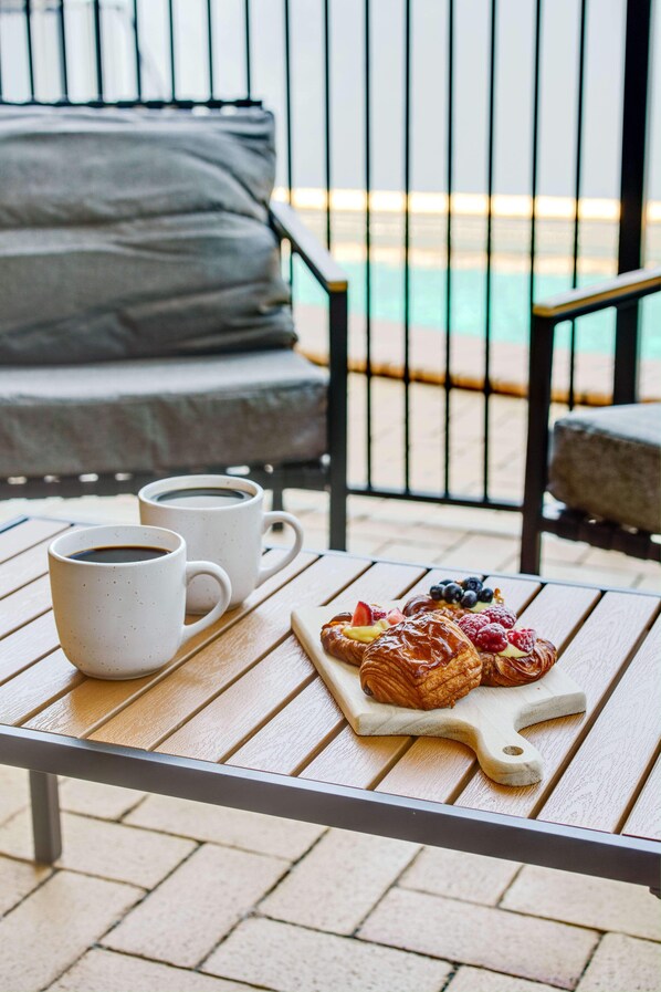 A table with two white cups of coffee and a pastry board with croissants and berries.