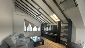 Una sala de estar moderna con un sofá modular, un televisor de pantalla plana y piso de madera.