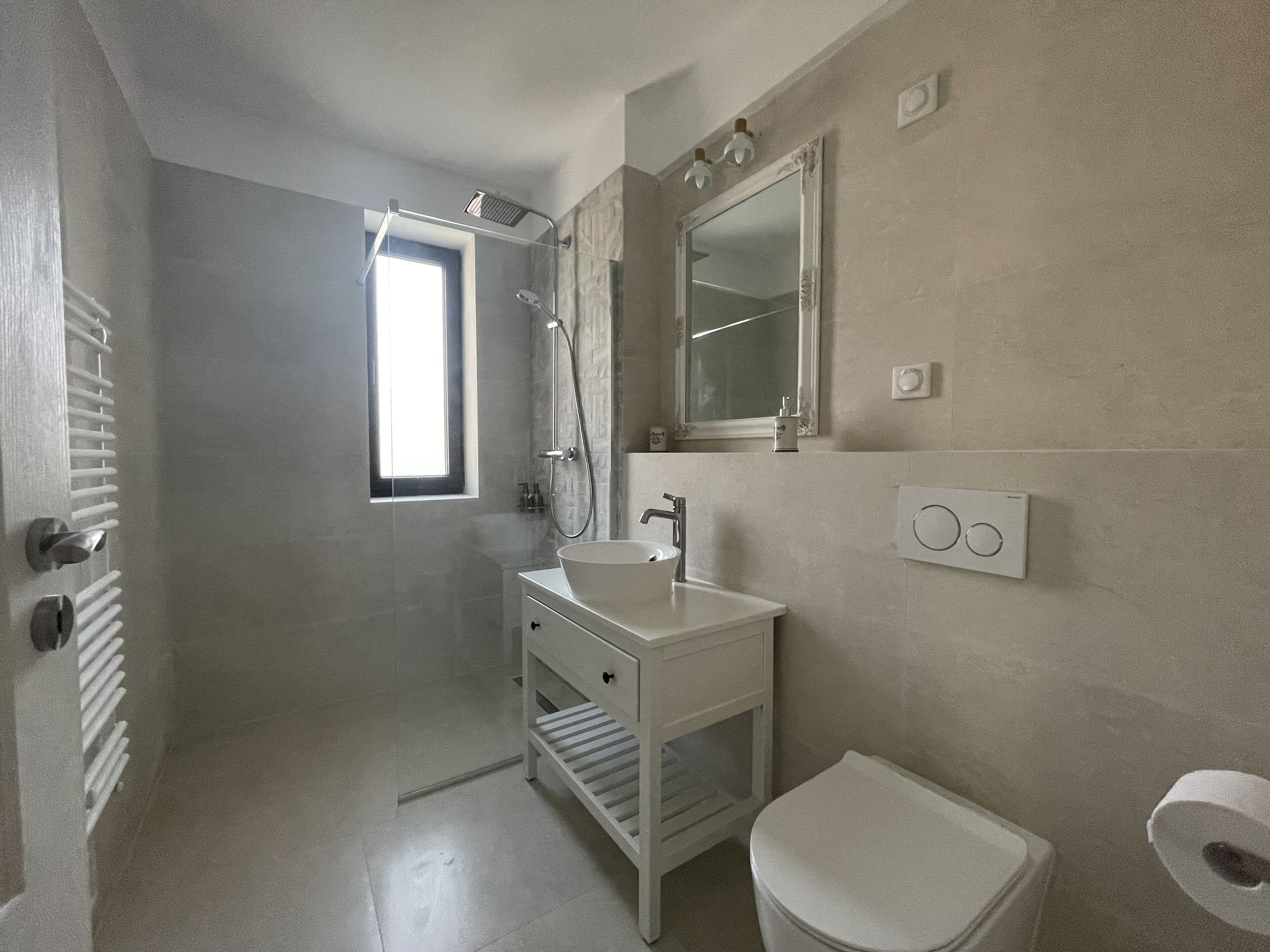 Un baño moderno con ducha, lavamanos e inodoro.