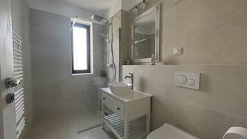 Un baño moderno con ducha, lavamanos e inodoro.