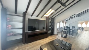 Una sala de estar moderna con televisor de pantalla plana, mueble de entretenimiento de madera oscura y una mesa de centro de vidrio.