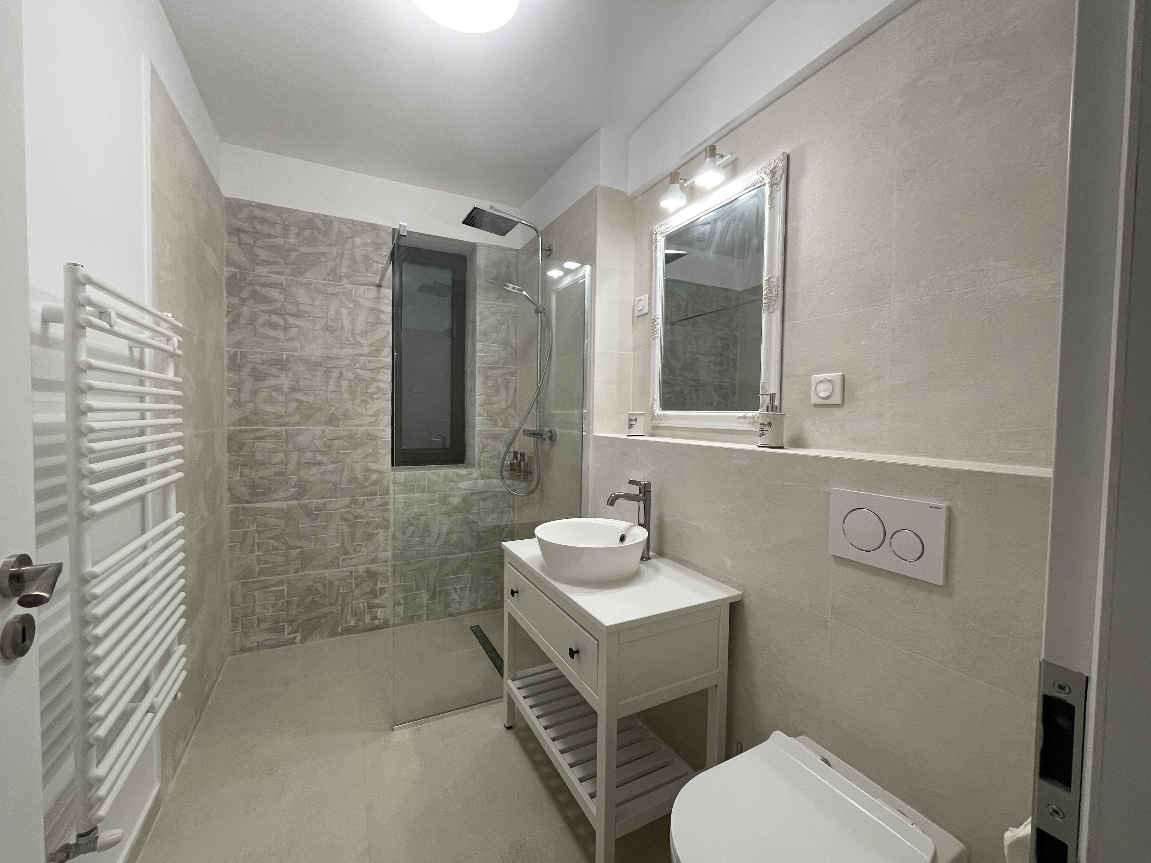 Une salle de bain moderne avec un mur en pierre, un lavabo blanc, un miroir et des toilettes.