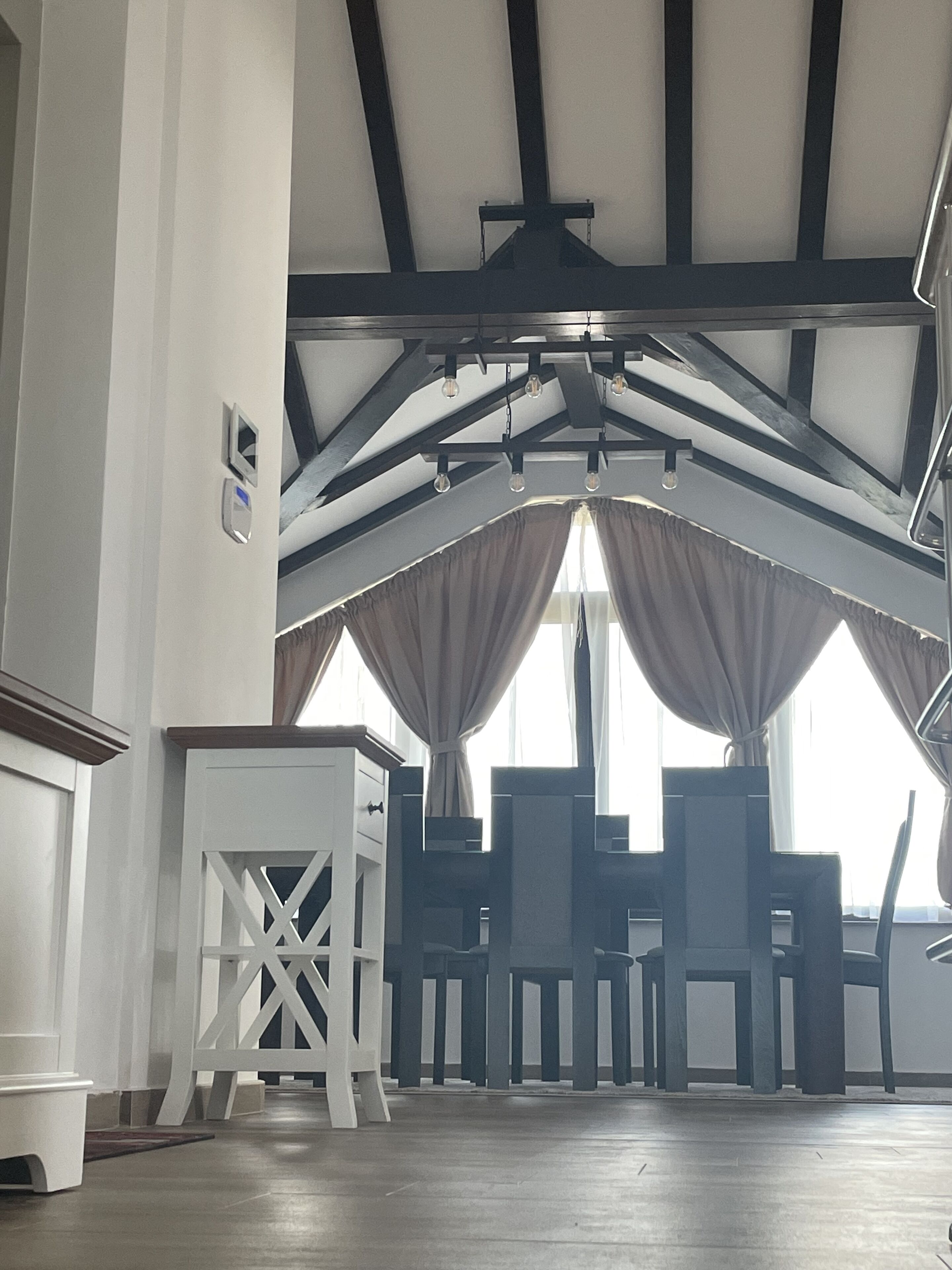 Amplia habitación con techo alto, ventanas grandes con cortinas y una moderna disposición de asientos.