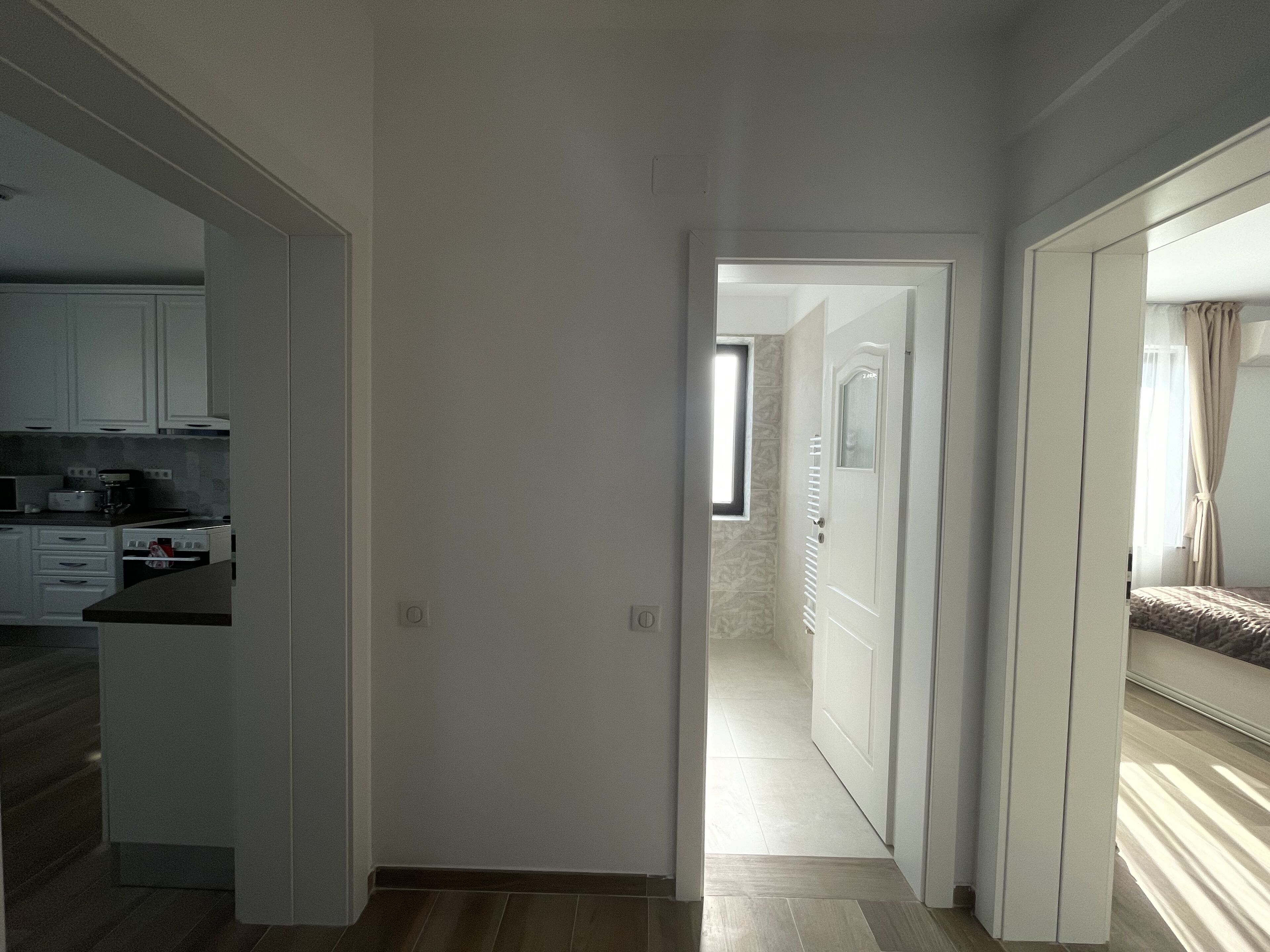 Un couloir étroit, avec une cuisine sur la gauche, une chambre à coucher sur la droite et une porte donnant sur une autre pièce.