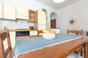Een keuken met houten kastjes, een fornuis en een fruitschaal op tafel.