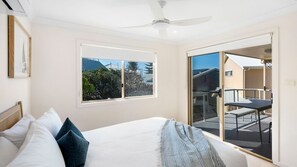 Une chambre à coucher avec un lit, des oreillers, une fenêtre et un balcon équipé d’une table et de chaises.